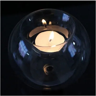 Handmade round hollow glass candle ball in three sizes on a table.