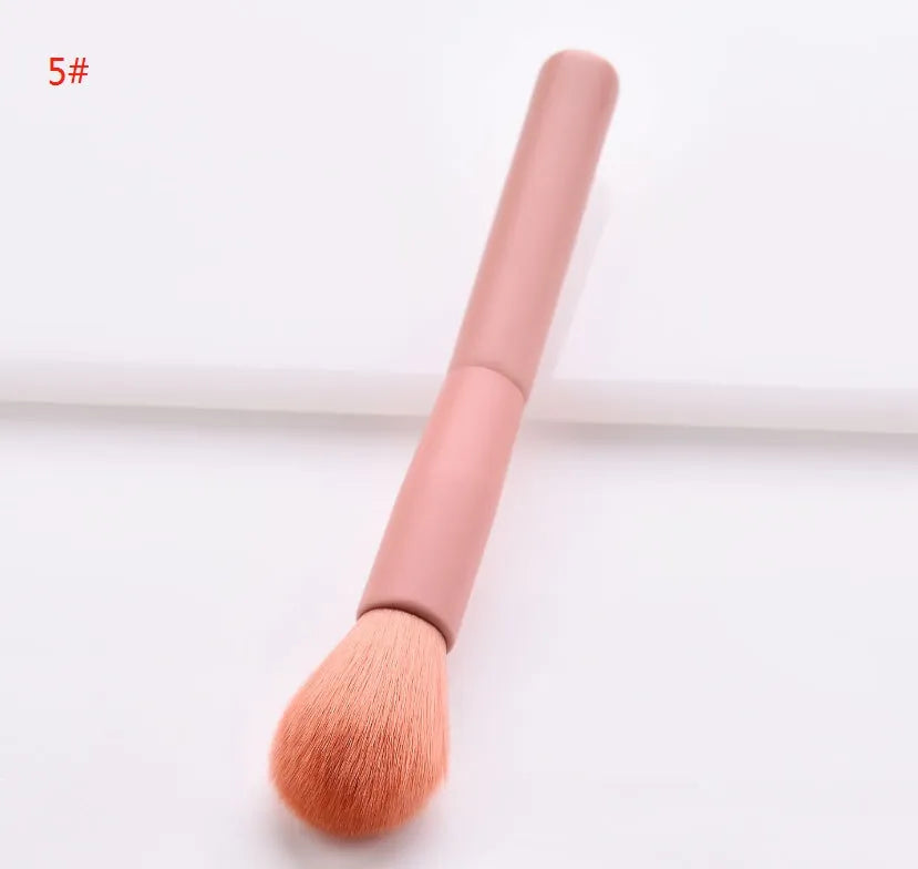 Ten cosmetic makeup brushes with wooden handles arranged showing various brush head shapes and sizes