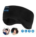 Black Bluetooth sleep mask with built-in speakers lying flat on a surface with a charging cable.