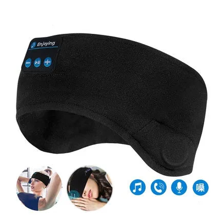 Black Bluetooth sleep mask with built-in speakers lying flat on a surface with a charging cable.