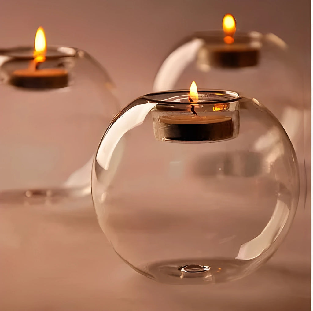Handmade round hollow glass candle ball in three sizes on a table.