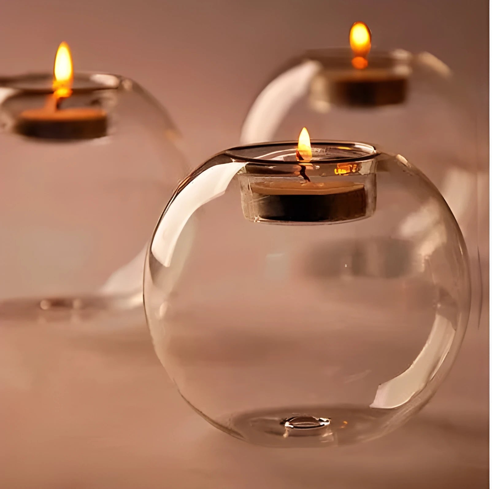 Handmade round hollow glass candle ball in three sizes on a table.