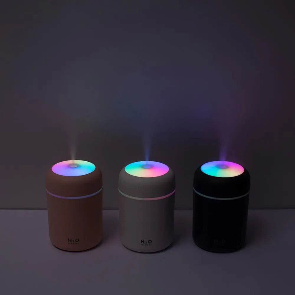 Pink USB-powered mini humidifier with colourful lights on a wooden desk