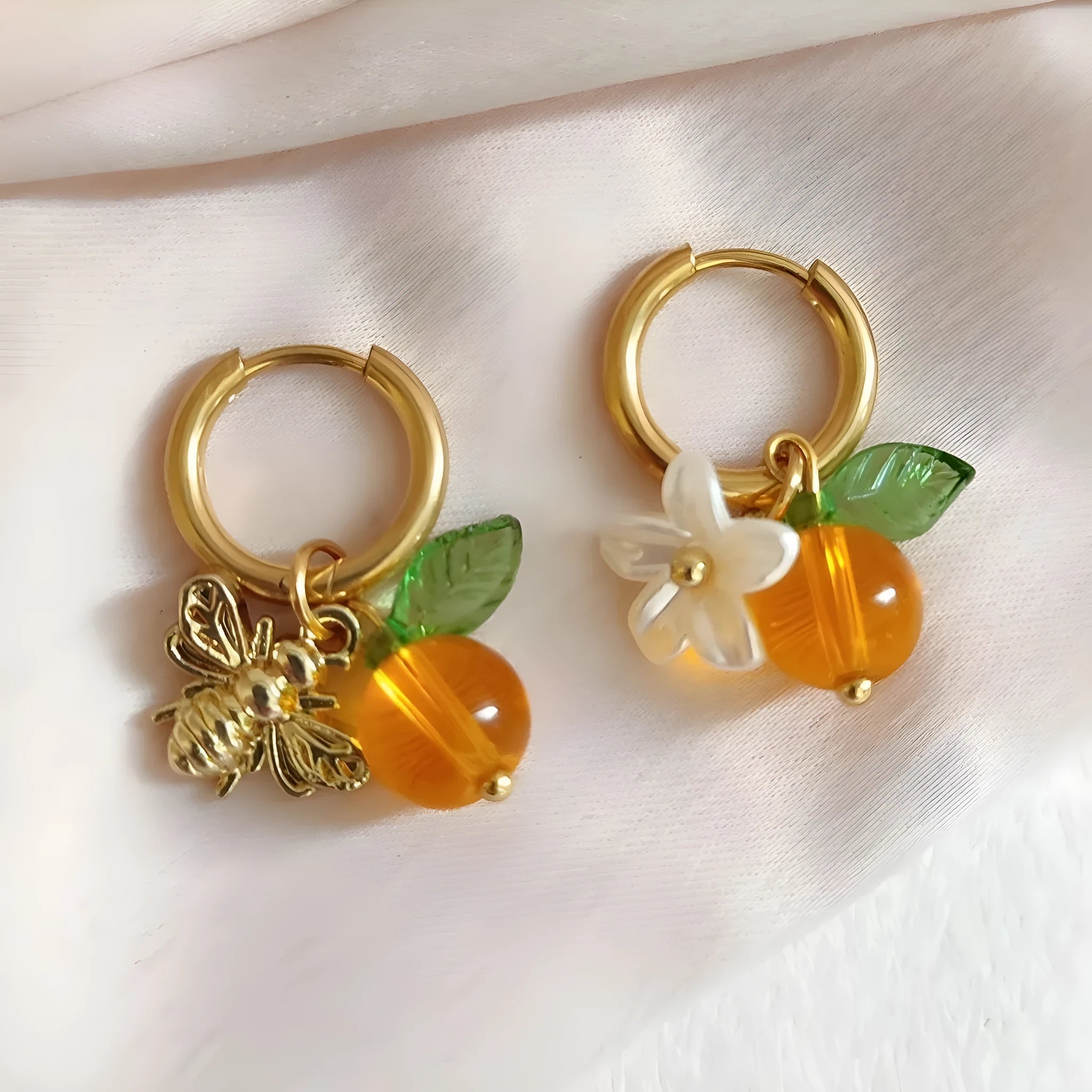 Pair of yellow acrylic sweet bee and honey fruit shaped earrings on a white background