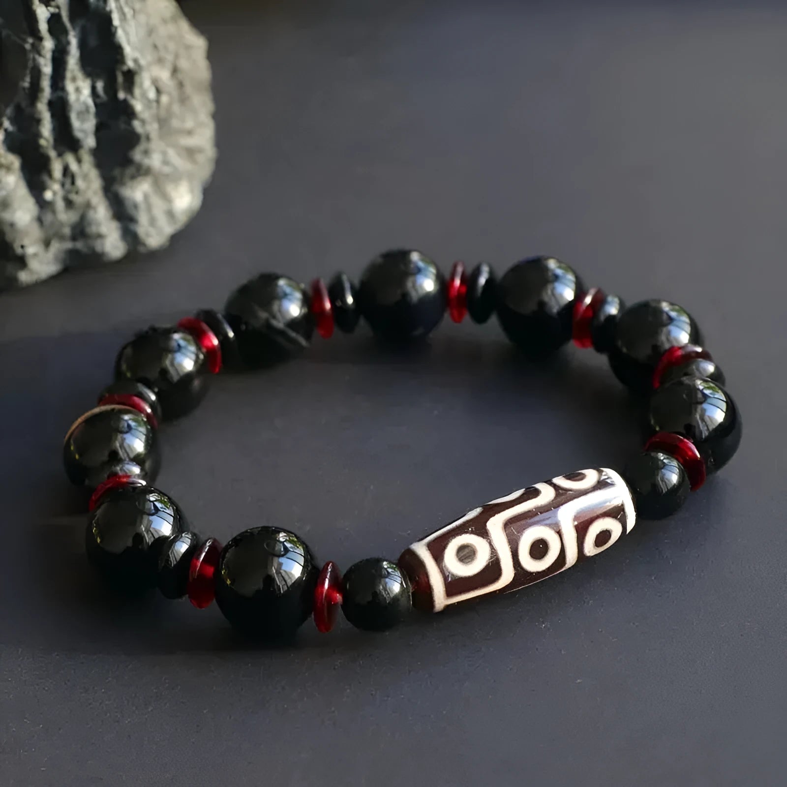 Hand-woven black agate dzi bead bracelet with geometric design measuring 11mm diameter