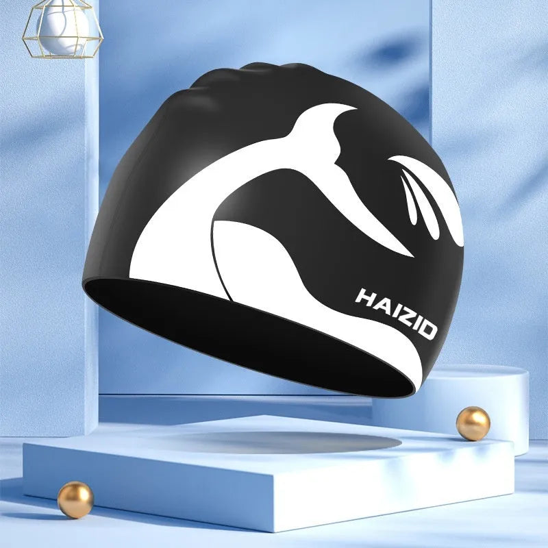 Close-up of a grey silicone swim cap with a whale tail pattern and integrated ear protectors.