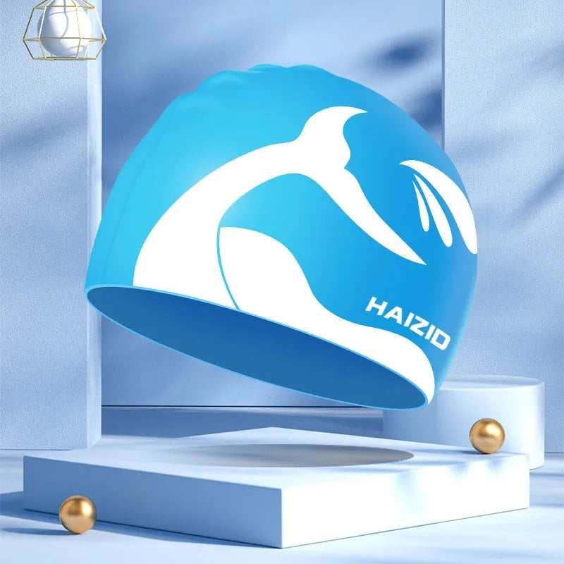 Close-up of a grey silicone swim cap with a whale tail pattern and integrated ear protectors.