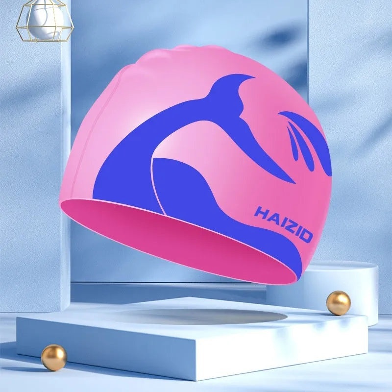 Close-up of a grey silicone swim cap with a whale tail pattern and integrated ear protectors.