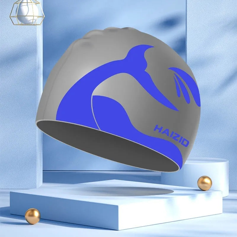 Close-up of a grey silicone swim cap with a whale tail pattern and integrated ear protectors.