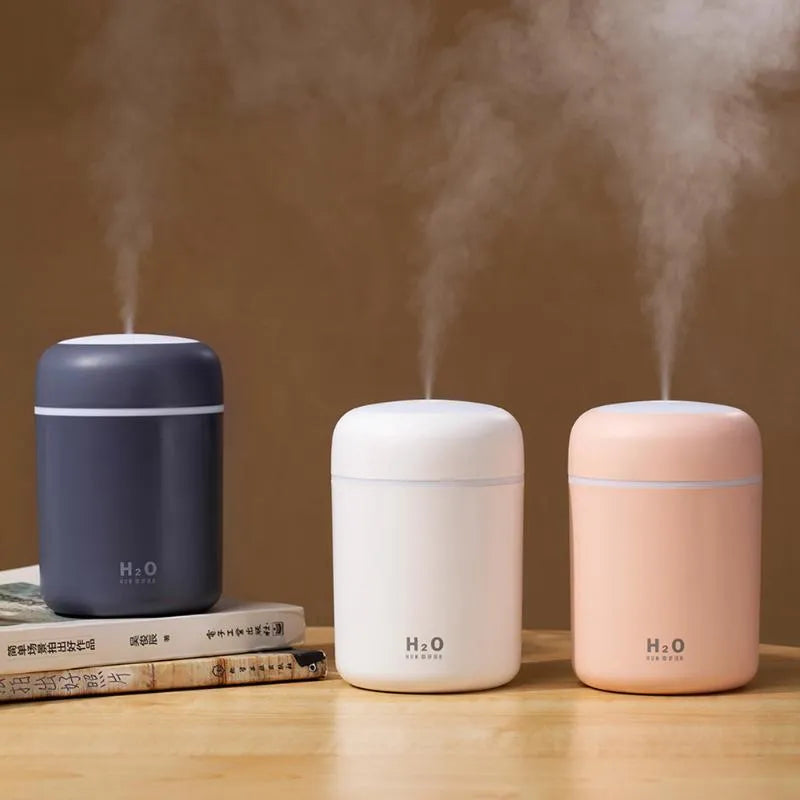 Pink USB-powered mini humidifier with colourful lights on a wooden desk