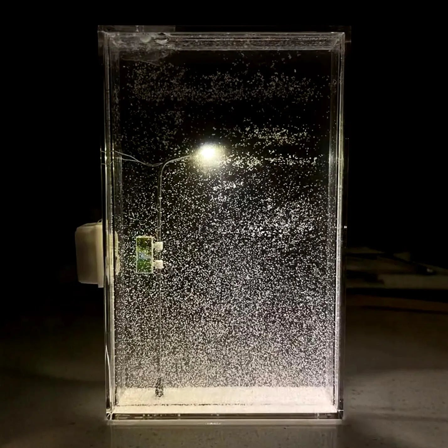 DIY snowy night light kit showing assembled snowflake street lamp scene with warm LED glow on a desktop.