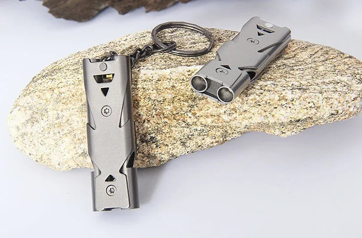 Keychain whistle in black with metal lanyard ring on a plain background