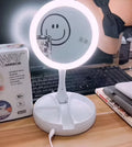 White foldable LED vanity mirror with USB charging port and built-in storage compartments on a table.