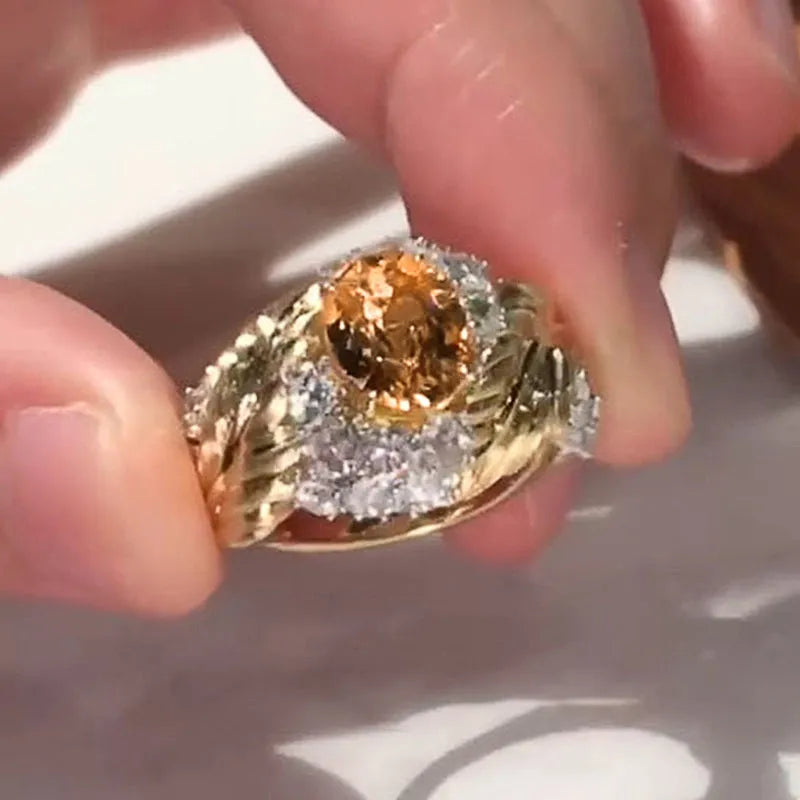 Gold coloured women's ring with embossed feather design and yellow zircon stones.