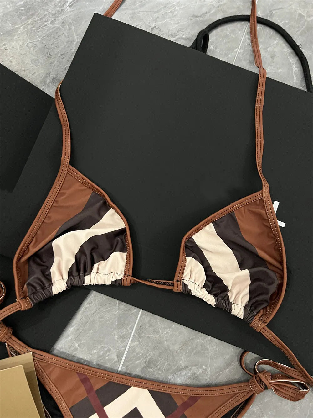 Women's black and white floral bikini set with split briefs on a beach