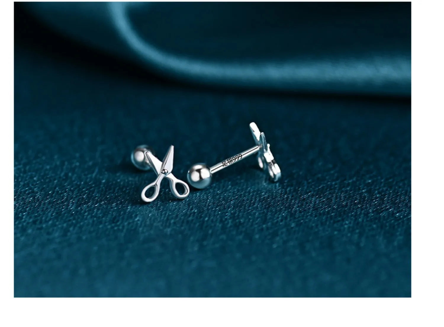 A pair of pure silver ear studs with a miniature scissors design on the screw-back fastener.