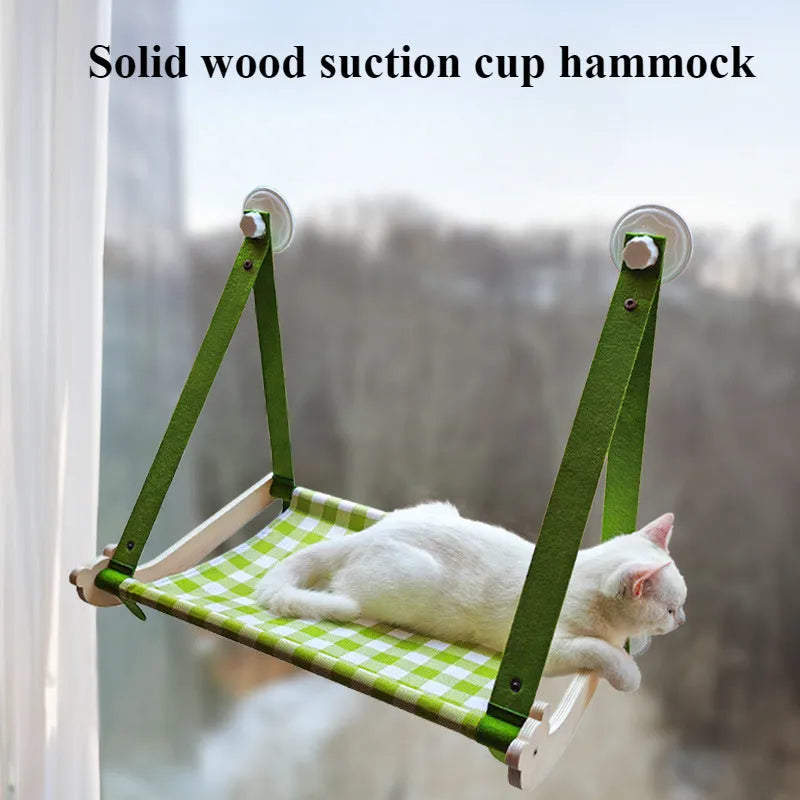 Pink wooden cat hammock with suction cups attached to a window, showing a removable cat paw print fabric seat.