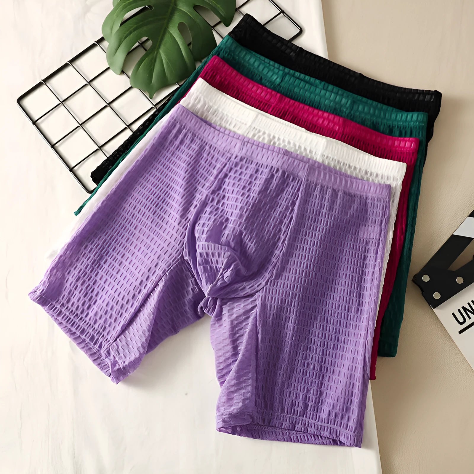 Men's solid colour lace boxer underwear with hip lifting design on a mannequin.