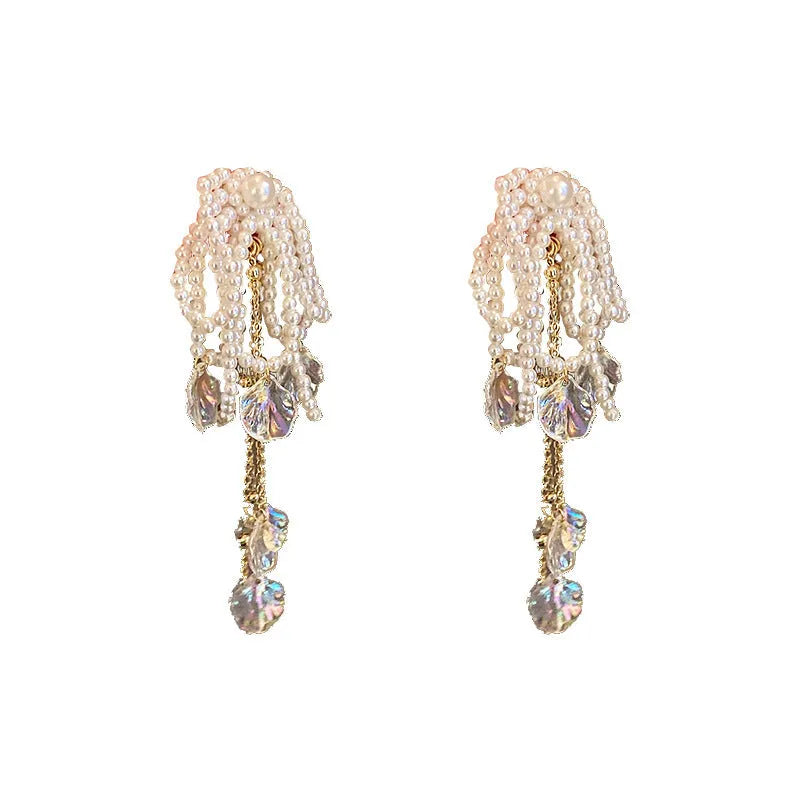 Gold long drop earrings with pearl, bow, tassel, and sequin detail on white background