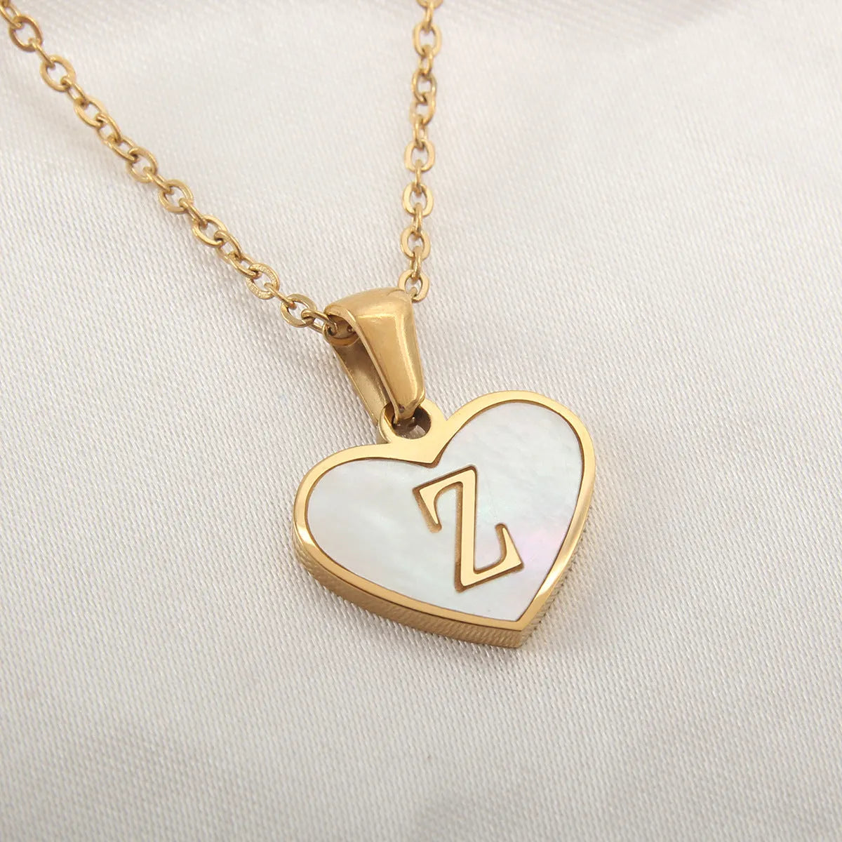 Gold plated heart-shaped necklace with a personalised initial letter and white shell detail on a 50cm adjustable chain.