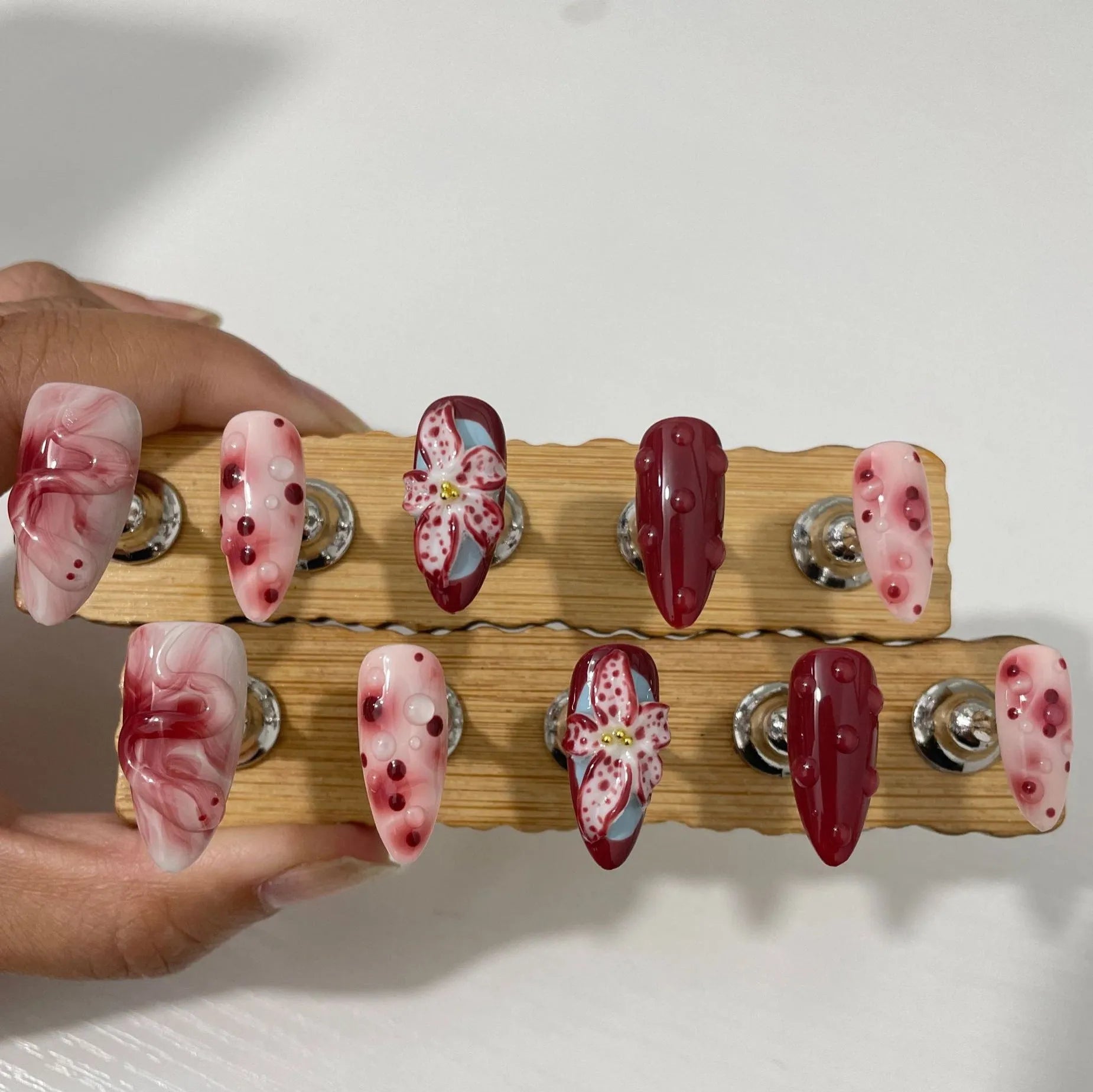 Hand-painted three-dimensional carved acrylic manicure nails in almond colour with floral and geometric patterns