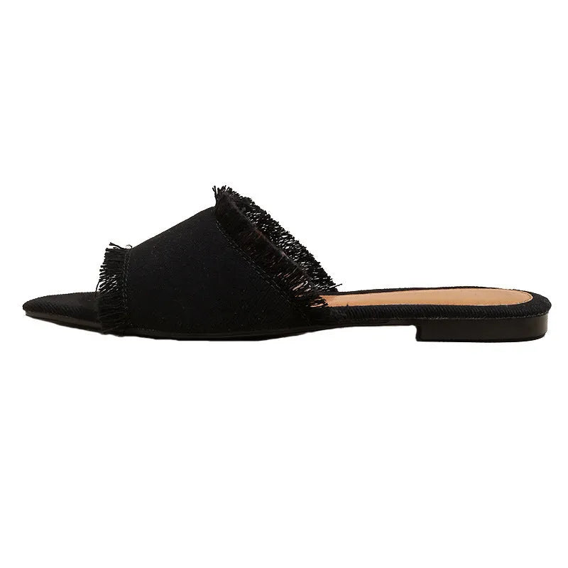 Women's denim flat slipper with leather lining, PVC sole, and a decorative tassel in a solid colour.