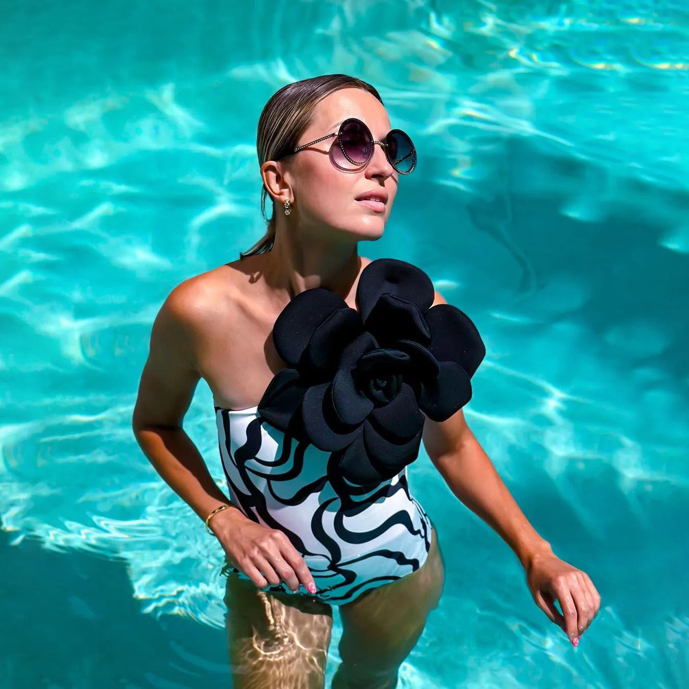 Black one-piece swimsuit with white three-dimensional flower design, form-fitting European American style.