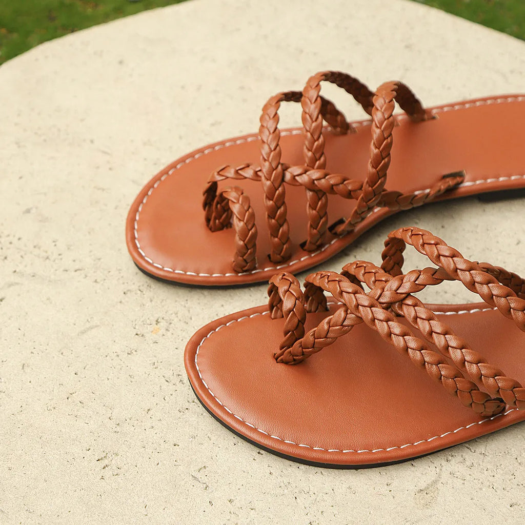Women's black woven clip-toe flat sandals with a rubber sole on a neutral background.