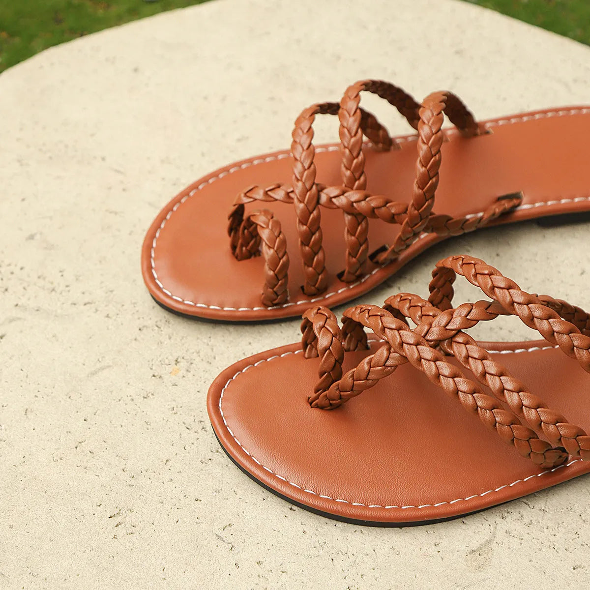 Women's black woven clip-toe flat sandals with a rubber sole on a neutral background.