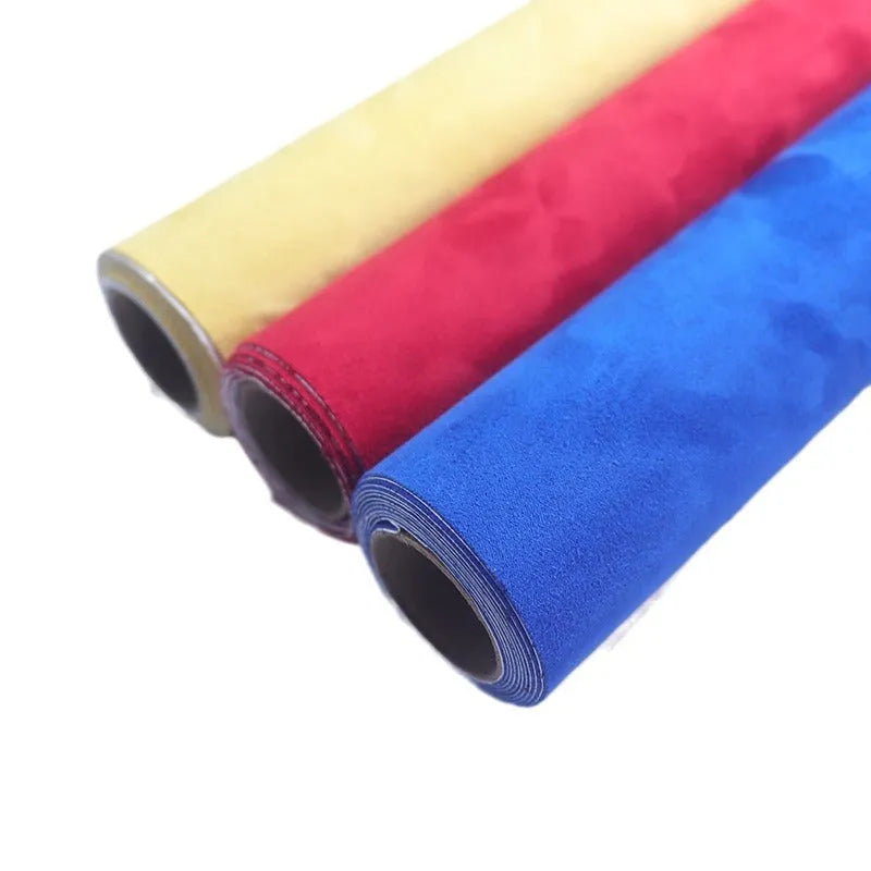 Roll of self-adhesive black leather suede fabric with adhesive backing visible, showing texture and a cut sheet sample.