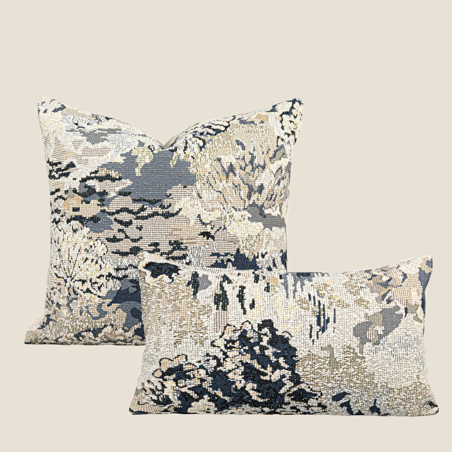 Antique blue square cushion with abstract botanical flower pattern on a grey sofa.