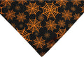 Black and orange reversible Halloween dog bandana with pumpkin and spider web patterns, showing adjustable neck strap.