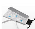 Mini foldable Bluetooth keyboard in black, open next to a smartphone on a wooden desk