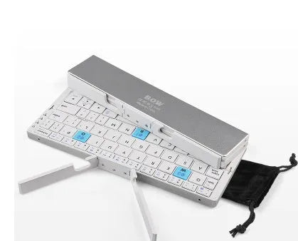 Mini foldable Bluetooth keyboard in black, open next to a smartphone on a wooden desk