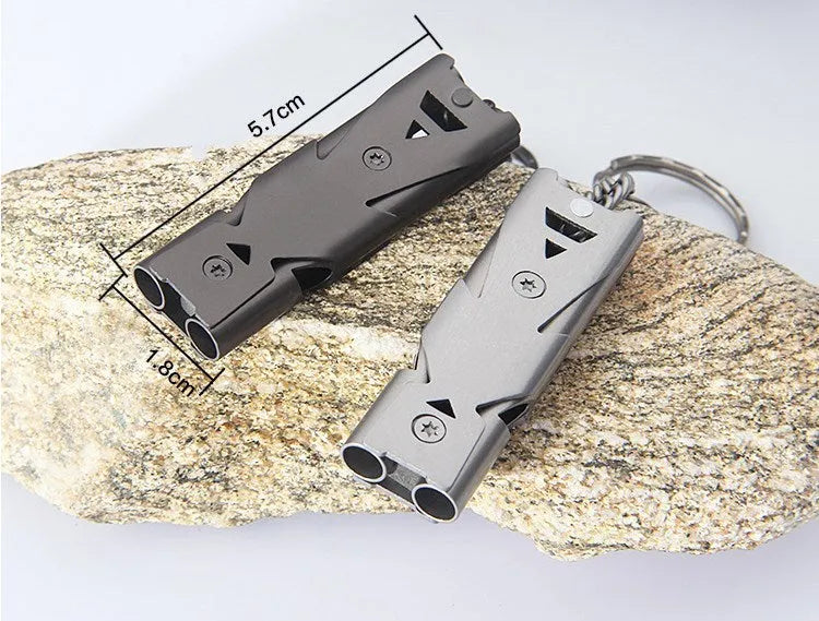 Keychain whistle in black with metal lanyard ring on a plain background