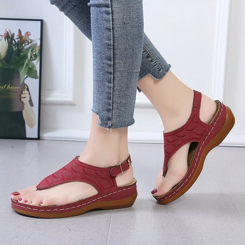 Women's red wedge heel sandals with an adjustable buckle strap on a white background