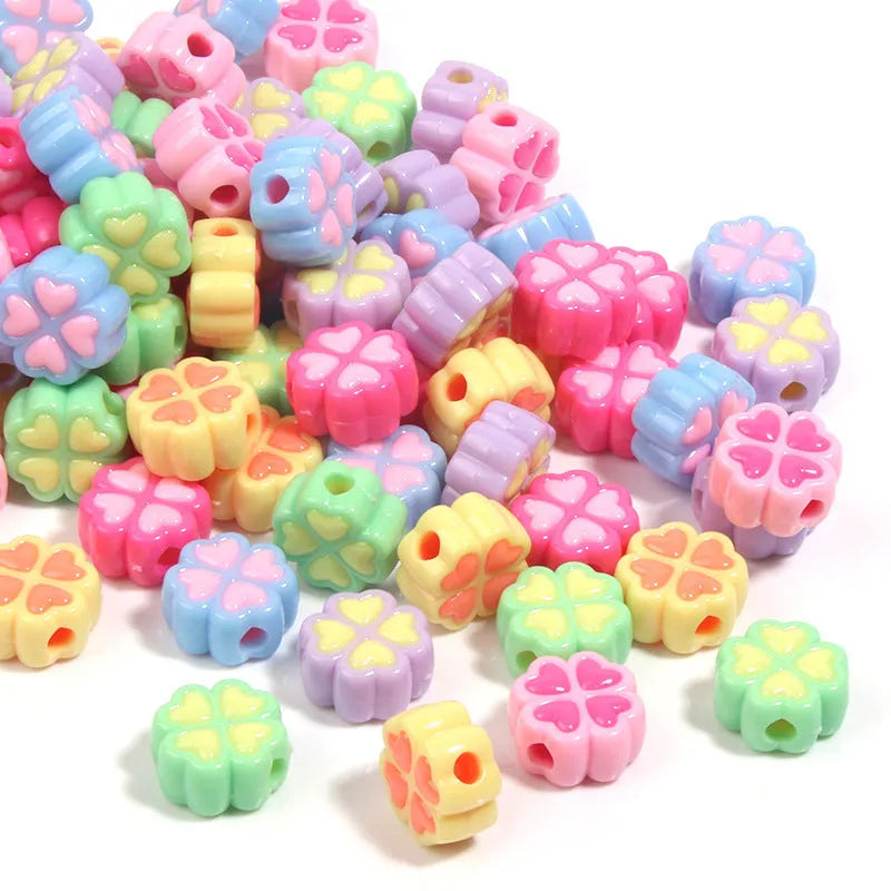 A selection of 15mm frosted acrylic beads showing a raised cartoon love and four-leaf clover pattern in various colours.