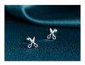 A pair of pure silver ear studs with a miniature scissors design on the screw-back fastener.