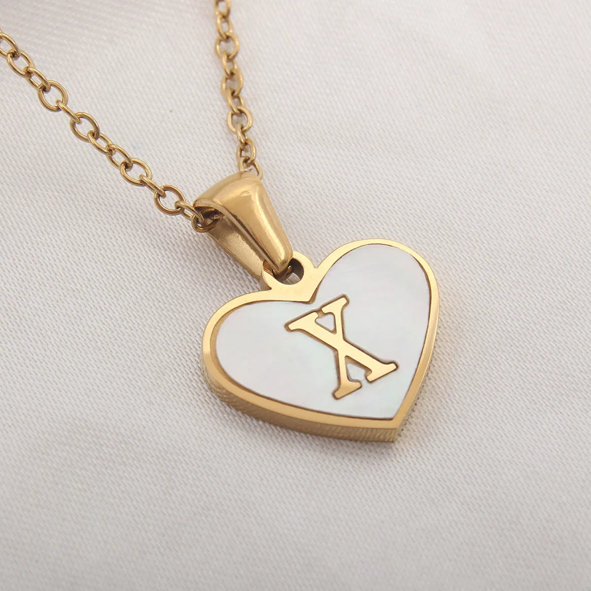 Gold plated heart-shaped necklace with a personalised initial letter and white shell detail on a 50cm adjustable chain.