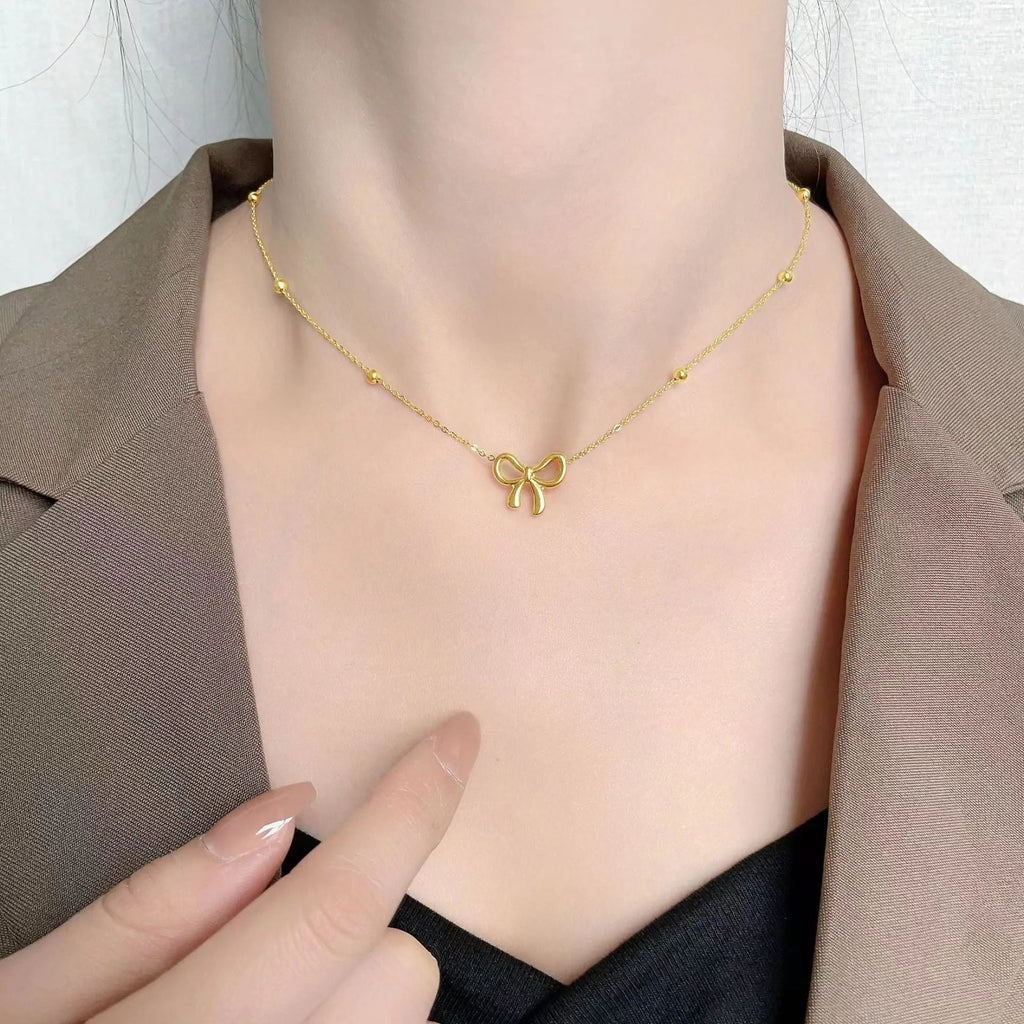 Gold-coloured titanium steel necklace with bow design and cross chain construction