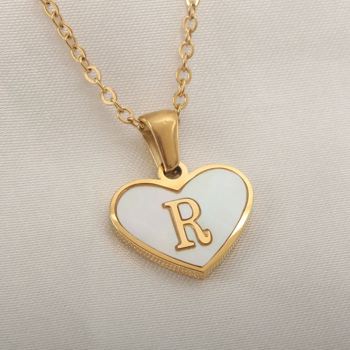 Gold plated heart-shaped necklace with a personalised initial letter and white shell detail on a 50cm adjustable chain.