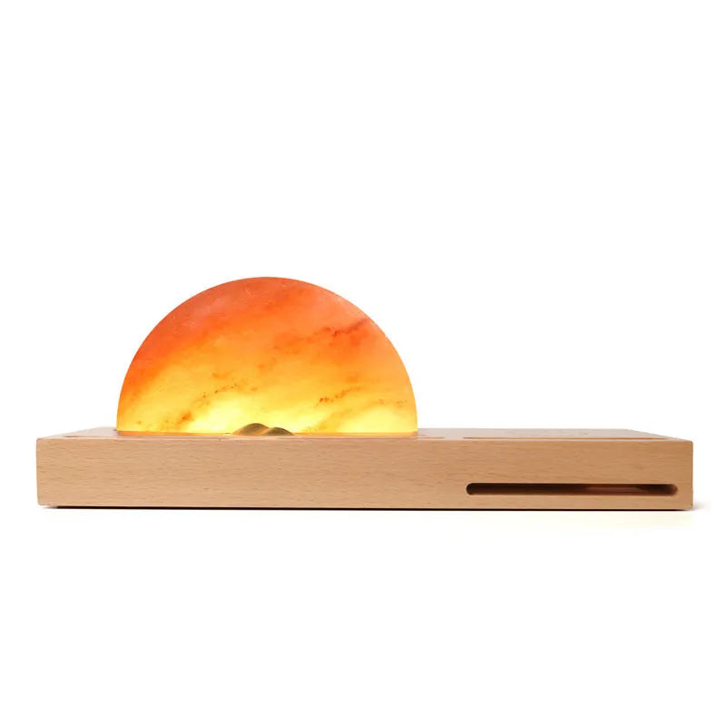Wooden base Himalayan salt lamp with wireless phone charging pad on top showing warm white glow.