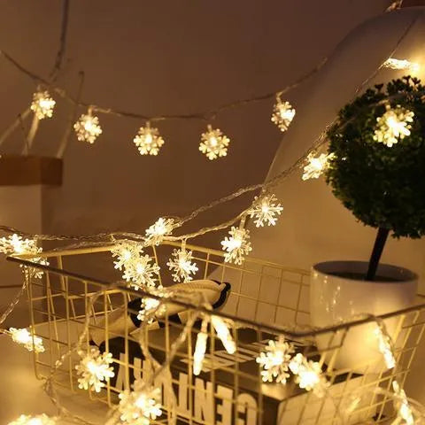 Battery powered LED snowflake string lights with star decorations lit on a dark background