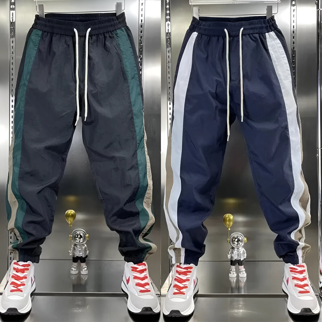Men's loose fit contrast stripe jogger sports pants in black, showing drawstring waist and tapered leg