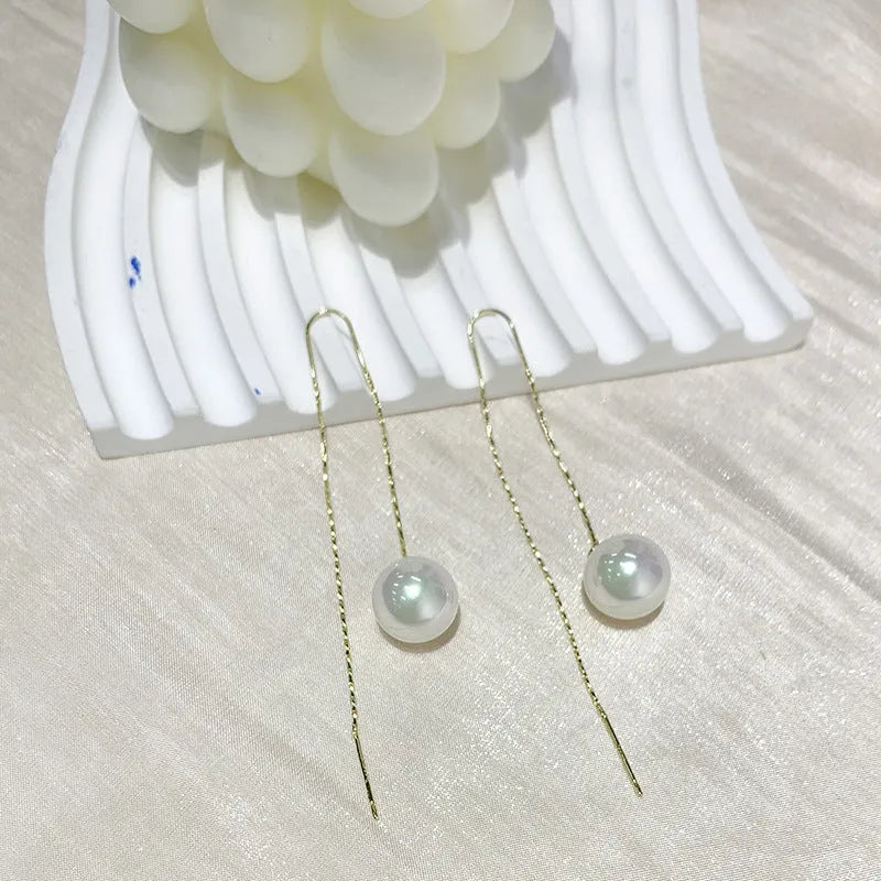 Fashionable long tassel pearl ear line drop earrings in gold finish on a white background