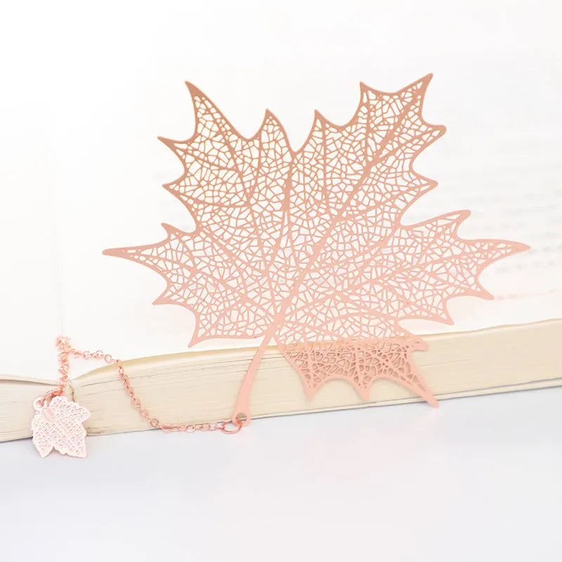 Brass metal bookmark with hollow leaf design and rose gold tassel in a presentation box.