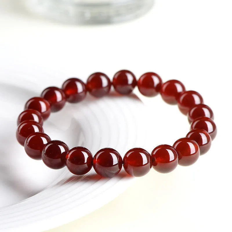 Natural orange red garnet ball bracelet with a silver Ruyi charm on a crystal beaded strand.