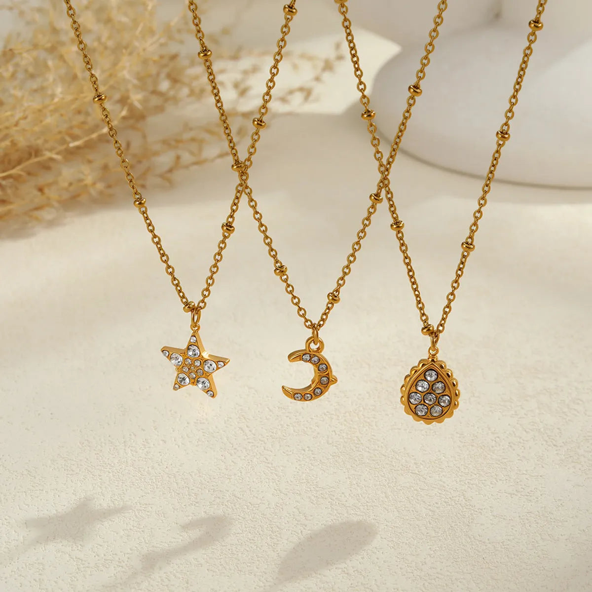 Set of three stainless steel geometric pendant necklaces with 18K electroplating: star, moon, and water drop shapes on regular chains.