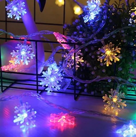 Battery powered LED snowflake string lights with star decorations lit on a dark background