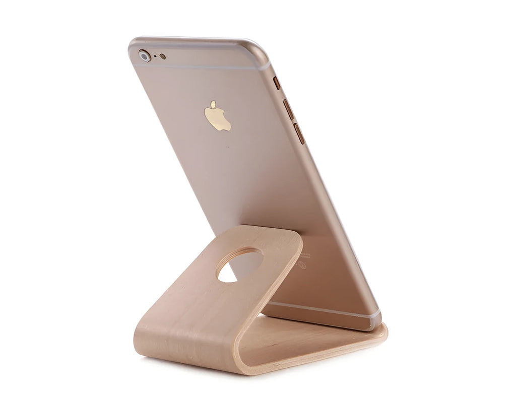 Wooden iPhone stand in walnut finish on a desk holding a mobile phone.
